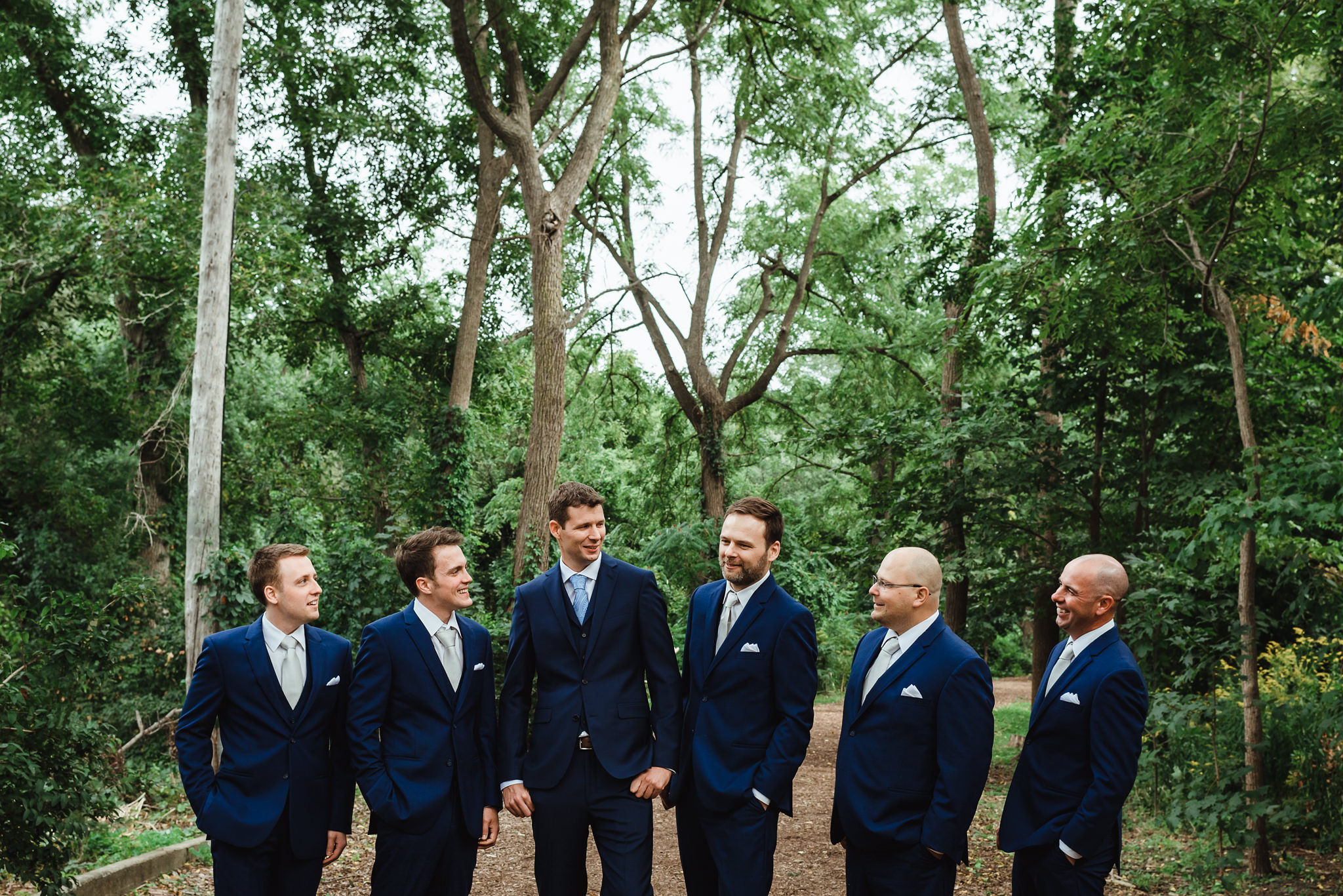 groom and his 5 groomsmen standing in blue suits in the gardens before wedding ceremony at La Paletta Mansion in Burlington Ontario