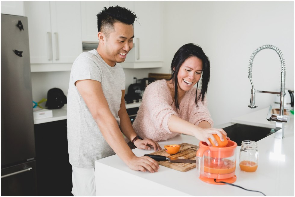 Couple squeezing oranges to make orange juice, during their Toronto lifestyle maternity photos. 