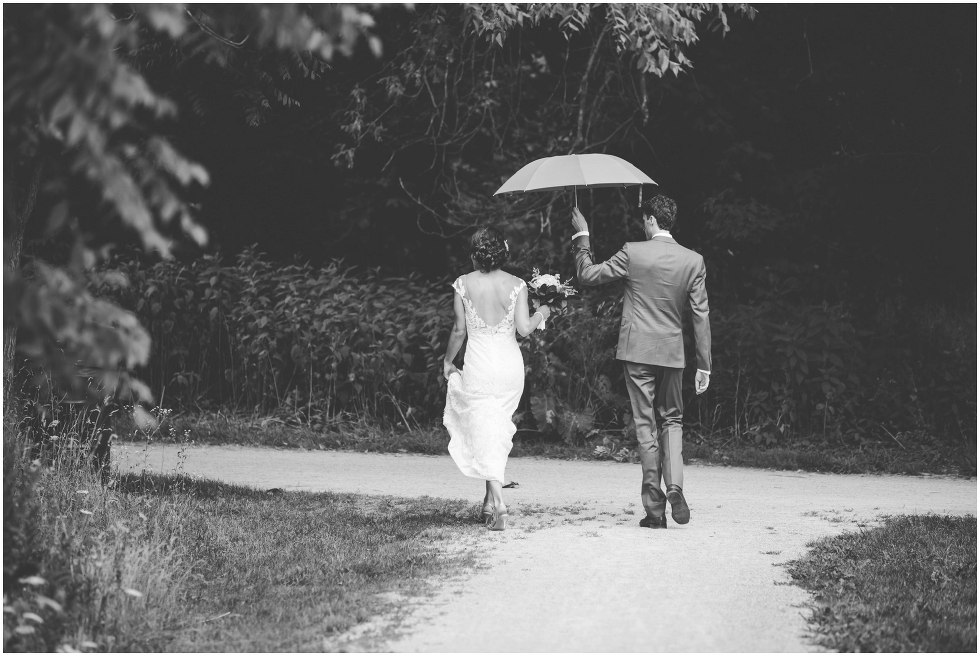 Groom holding and umbrella for the bride as they walk at Goldie Mill Ruins