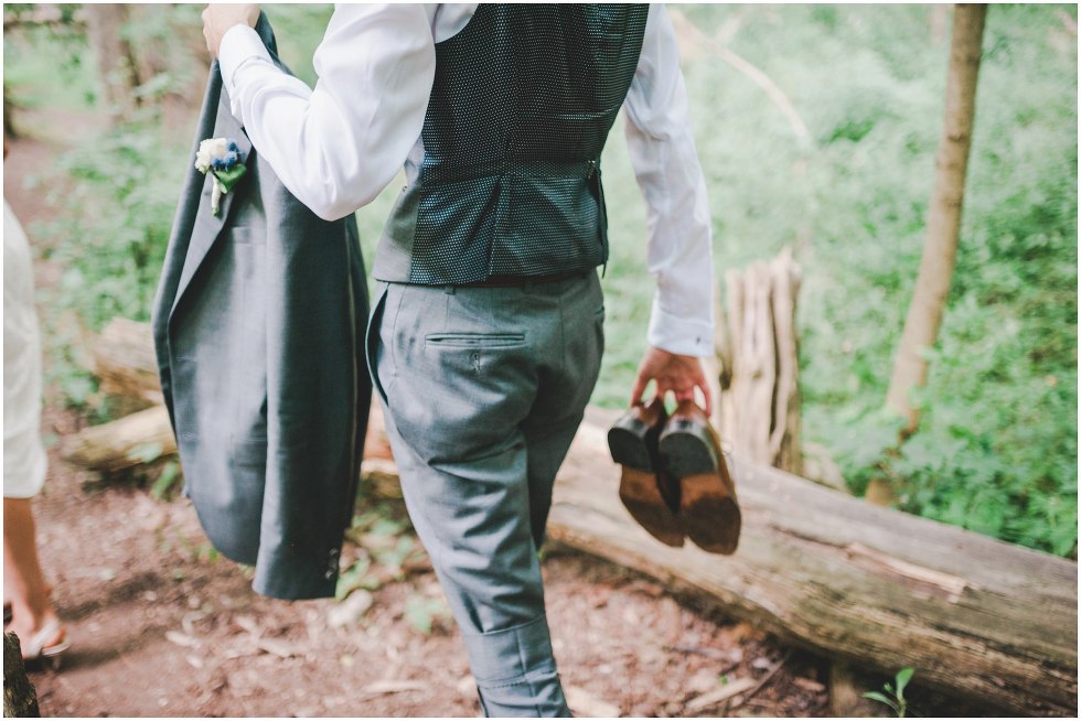 Groom walking while carrying shoes
