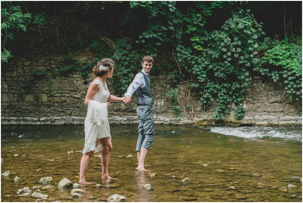 Bride and groom walking barefoot in the river