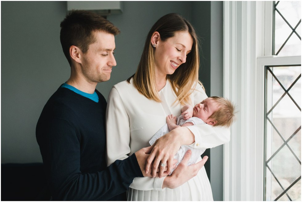 Parents holding and smiling at their daughter during their Toronto Newborn Lifestyle photos