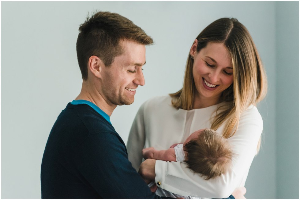 Parents smiling and holding their daughter during their Toronto Newborn Lifestyle photos
