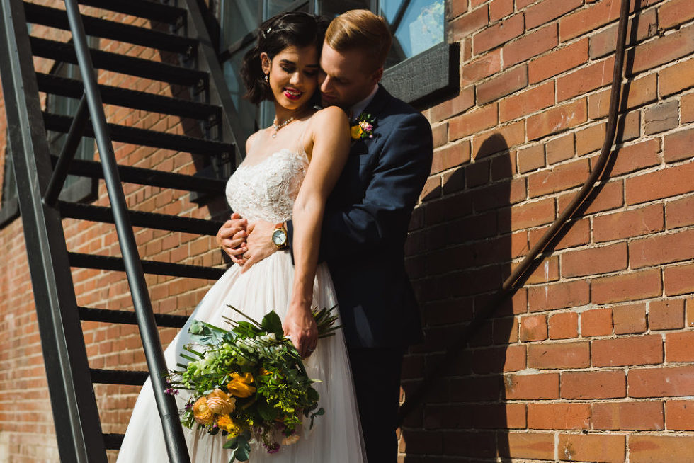 bride and groom in loving embrace on black fire escape staircase of the Jam Factory Toronto wedding photography