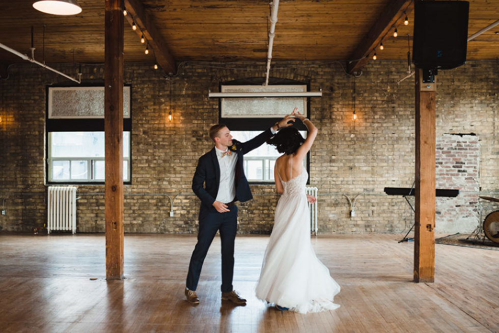 groom twirls his bride on dance floor inside Jam Factory Toronto wedding photography