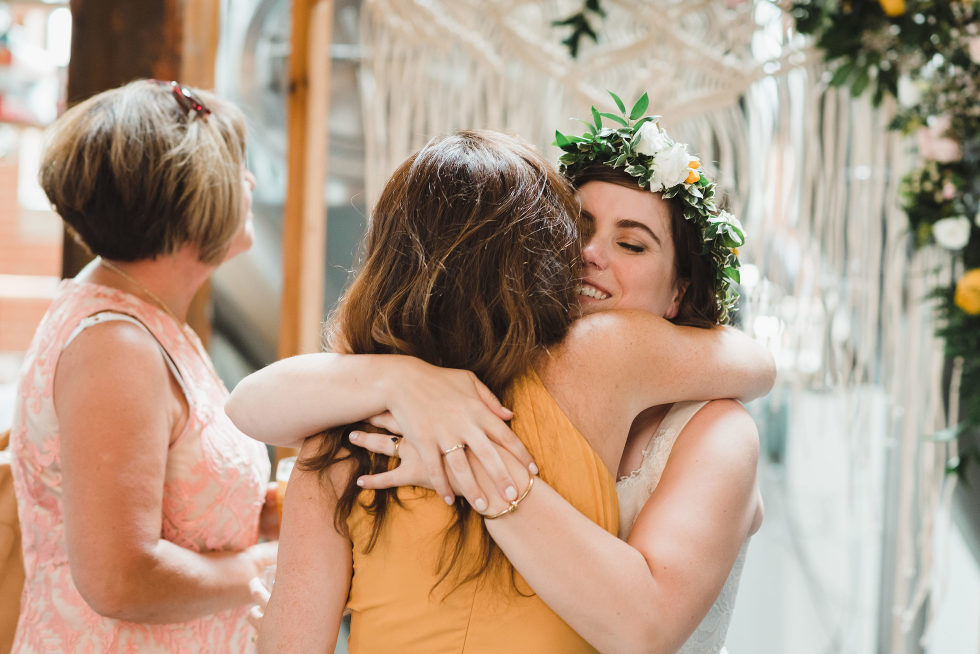 bride hugging a wedding guest Junction Craft Brewing Toronto wedding photographer Gillian Foster