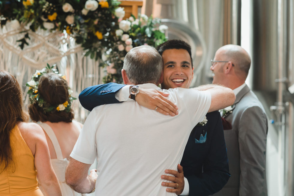 groom hugging a wedding guest Junction Craft Brewing Toronto wedding photographer Gillian Foster