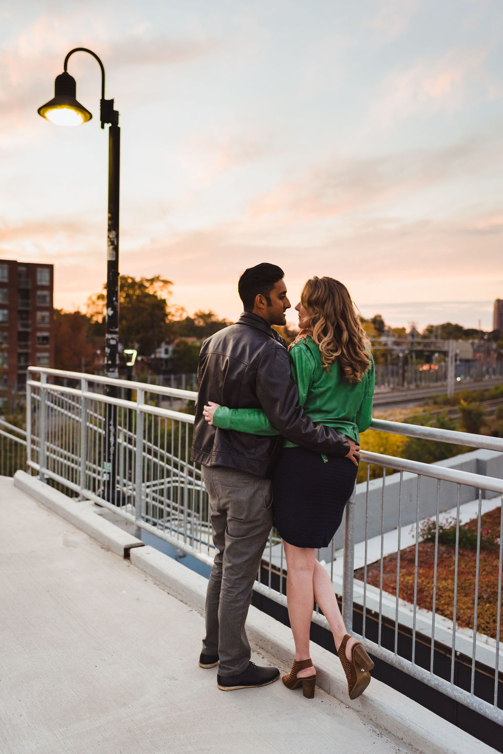 man and woman embracing each other on platform overlooking train tracks in the Junction, Toronto